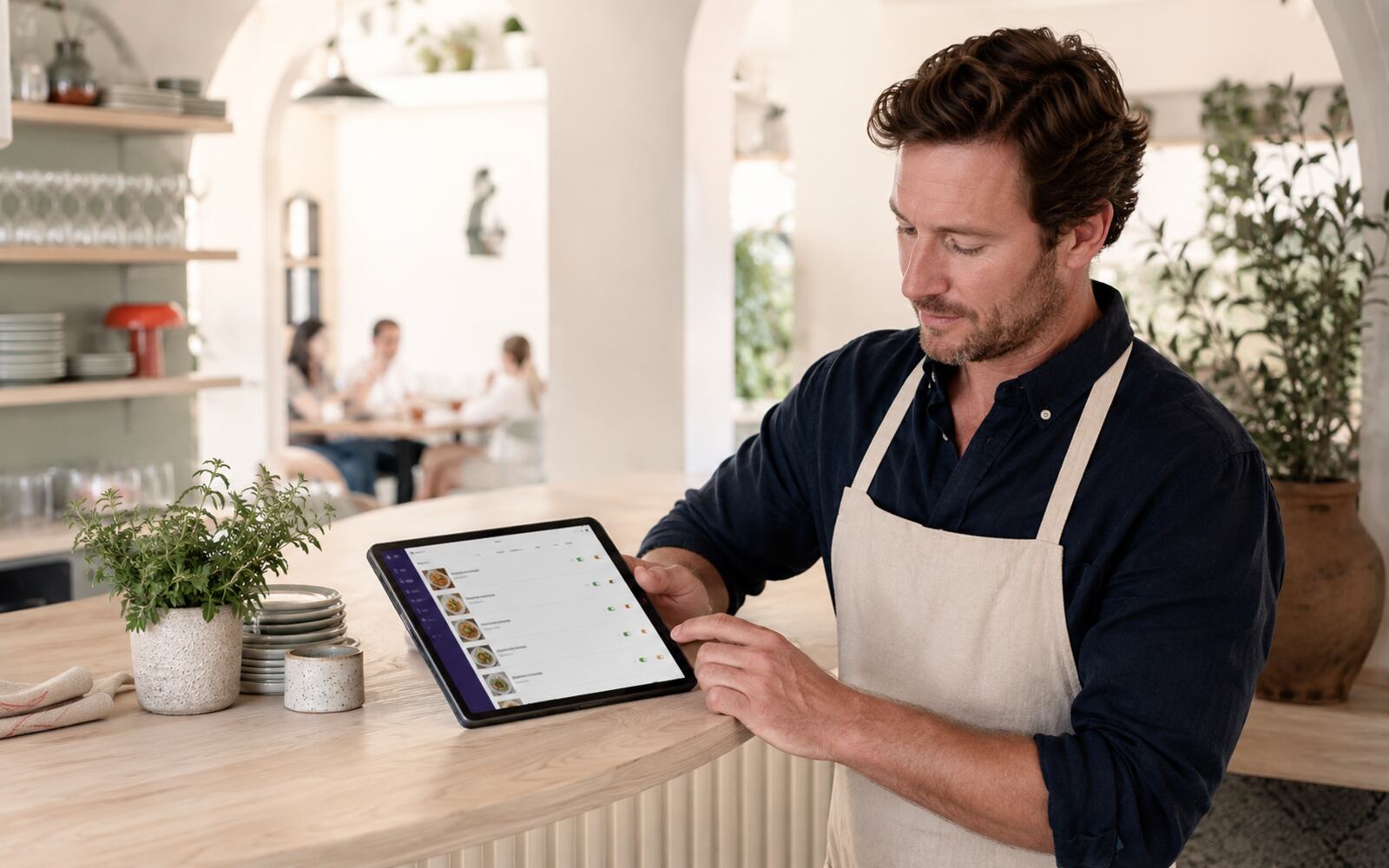 Un restaurateur compose sa carte sur une tablette, au comptoir de son établissement.